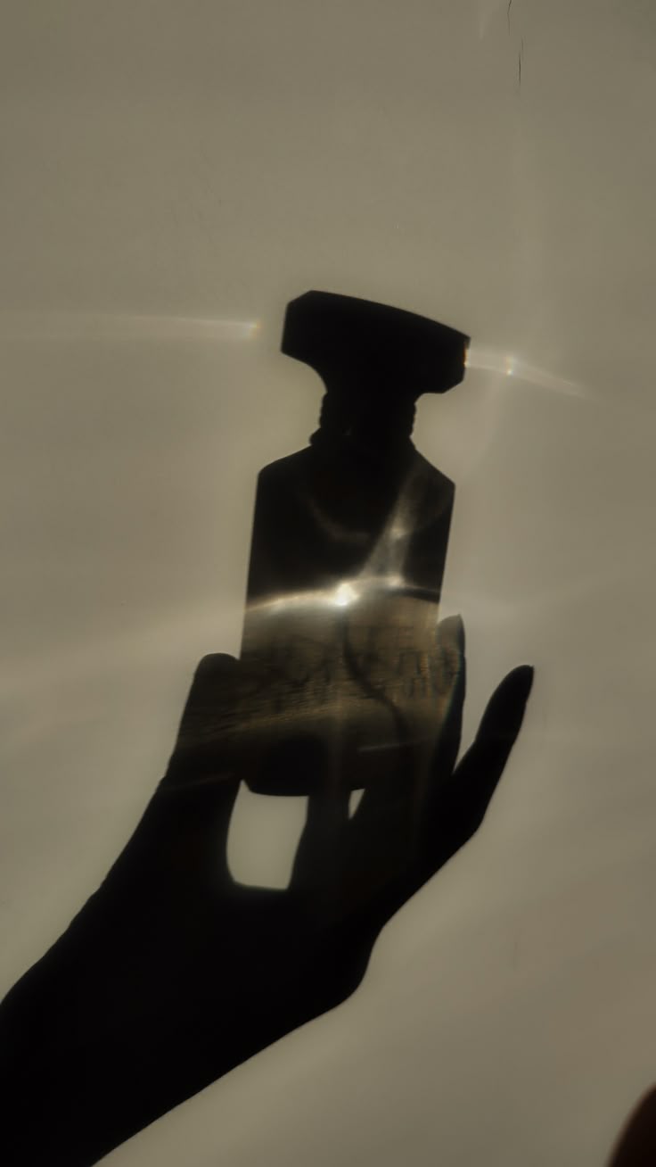 Силуэт парфюмерного флакона в руке на просвет